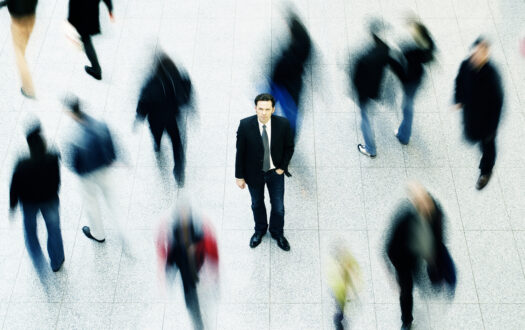 Business man surrounded by moving people, cross processed